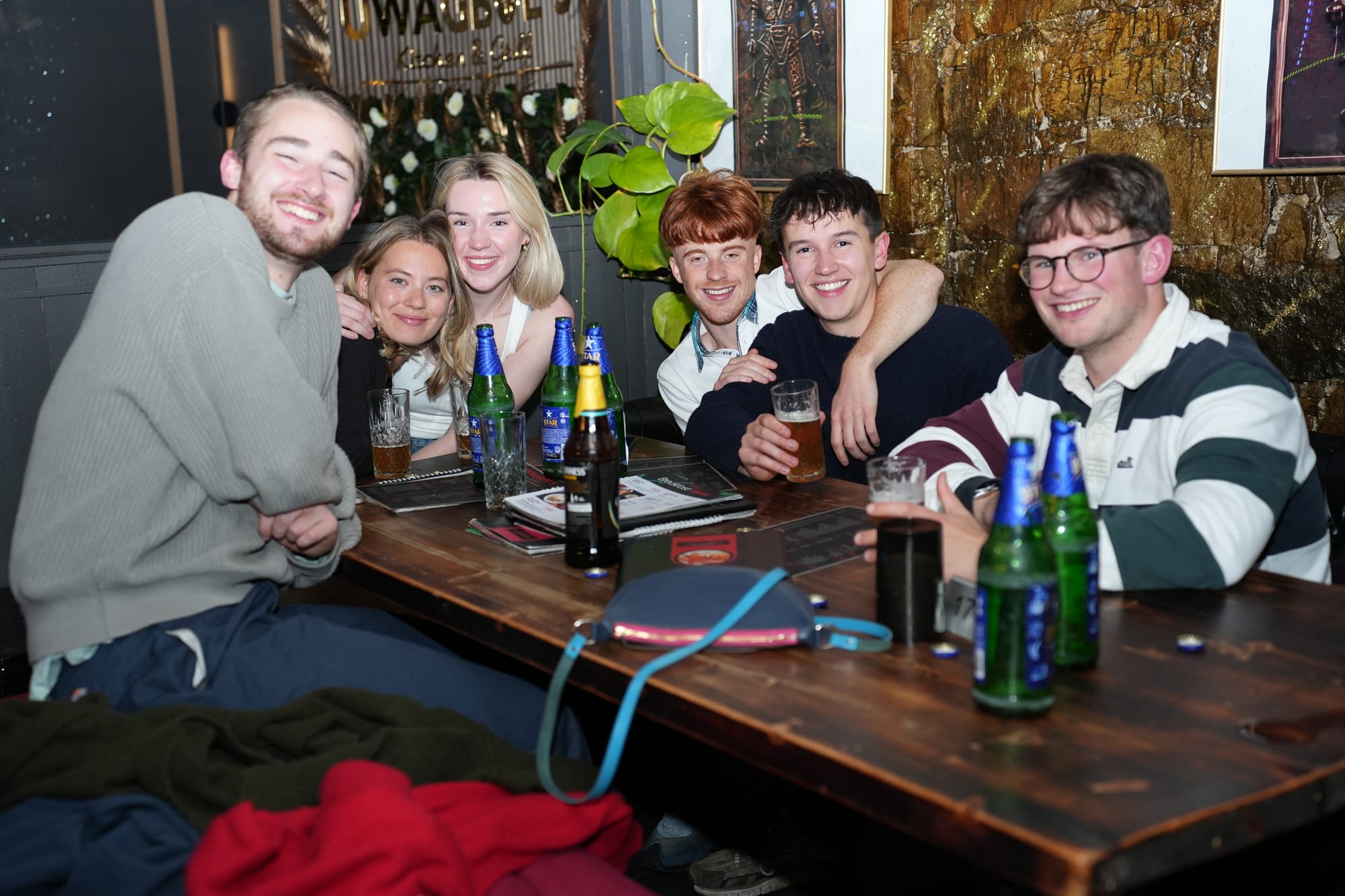 Friends celebrating together around a table at Uwagboe's Kitchen & Grill