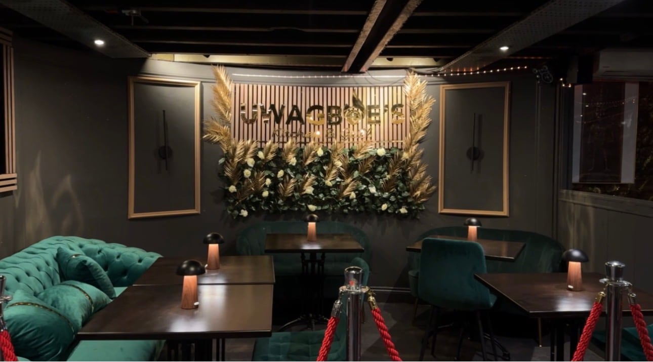 Inside Uwagboe's Kitchen & Grill: green velvet seating and the gold Uwagboe's wall
